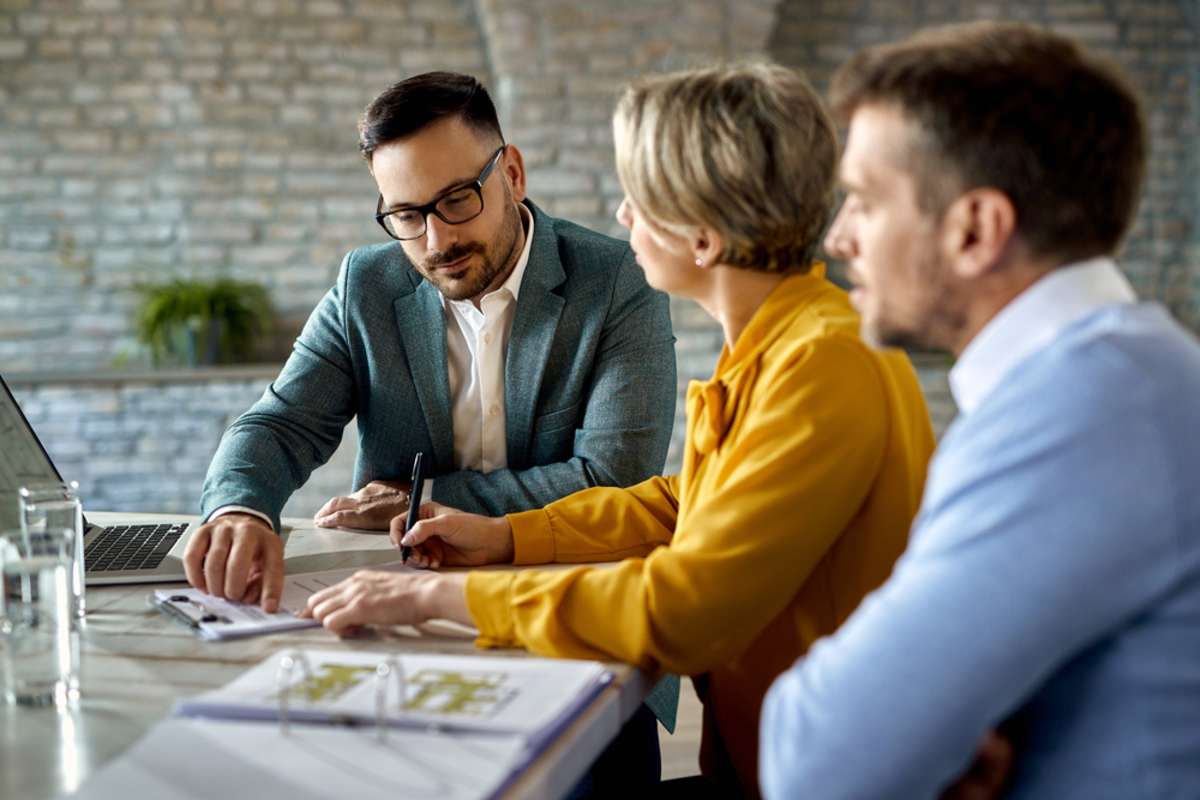 Real estate professional showing documents to clients, home-buying companies concept. 